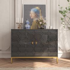 a living room with a large painting on the wall next to a black and gold cabinet