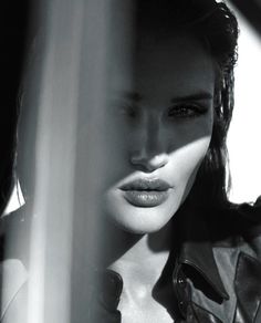 black and white photograph of a woman wearing a leather jacket looking out the window with her eyes closed