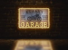 an illuminated garage sign on a brick wall with a light shining in the dark room