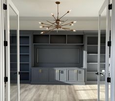 an empty room with built in bookshelves and lights hanging from the ceiling above