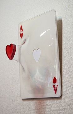 an ace playing card hanging on the wall with hearts attached to it's sides