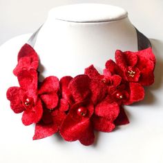 a white mannequin with red flowers on it's neck and pearls in the center