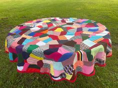 a patchwork table cloth is sitting on the grass in front of a field with green grass