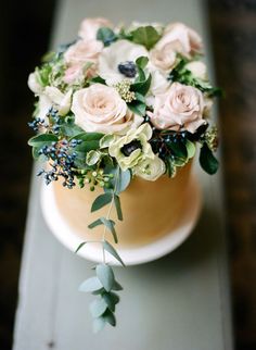 a cake decorated with flowers and greenery on a table