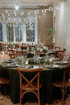 a dining room with tables and chairs covered in green cloths, lit by fairy lights