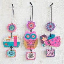 four wooden tags with different designs hanging on a white wall, one has an owl and the other has flowers