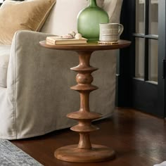 a green vase sitting on top of a wooden table next to a white couch in a living room