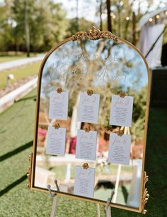 a gold mirror sitting on top of a grass covered field next to a sign that says,