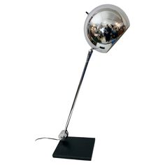 a chrome plated floor lamp with people reflected in the glass ball on it's base