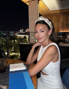 a woman wearing a tiara sitting at a table in front of a laptop computer