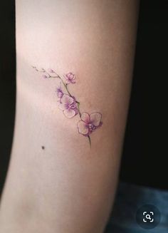 a small flower tattoo on the right side of the leg, with pink flowers growing out of it