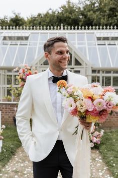 a man in a tuxedo holding a bouquet of flowers