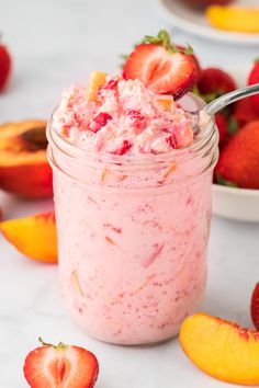 a jar filled with fruit salad next to sliced peaches and strawberries on the table