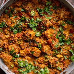 a pan filled with meat and vegetables covered in cilantro sauce, garnished with parsley