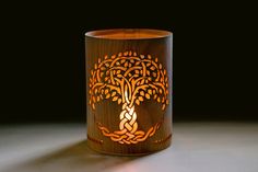 a wooden candle holder with an intricate tree design on the front and sides, sitting on a table