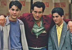 three young men standing next to each other in front of cardboard boxes with their arms around one another