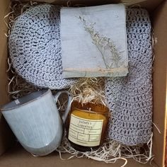 an open box containing a mug, napkins and a jar with honey in it