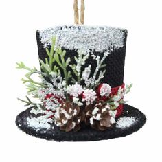 a black top hat with flowers and pine cones on the front is decorated with white frosting