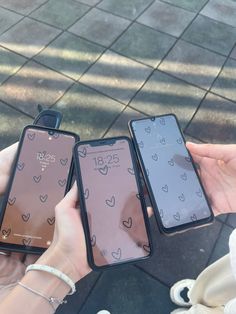 two people holding up their iphones with hearts on them