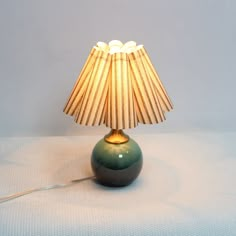 a green table lamp sitting on top of a white sheet covered floor next to a light bulb