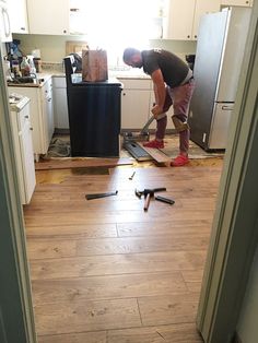 a man standing on top of a hard wood floor next to a refrigerator freezer