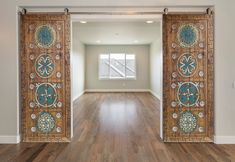 an empty living room with wooden floors and decorative door panels on the front entrance doors