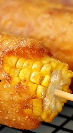 corn on the cob is being held by chopsticks