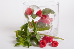 raspberries and mint leaves in a glass with ice cubes on the side