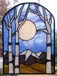 a stained glass window with trees and mountains in the background