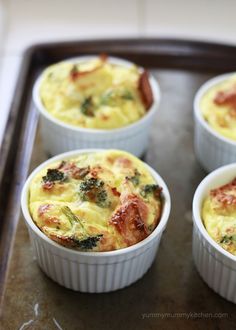 four small cups filled with food sitting on top of a pan covered in broccoli