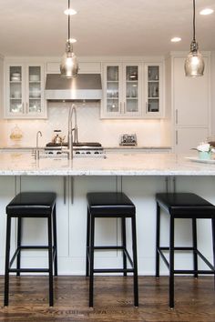 three stools sit at the center of a kitchen island