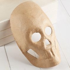 a wooden mask sitting on top of a white floor next to a door way with holes in it