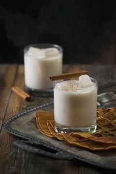 two glasses filled with white liquid and cinnamon sticks