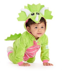 a baby in a green dragon costume crawling on the ground with its head turned to the side