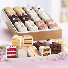 several different types of cakes on a white plate next to a box of chocolates