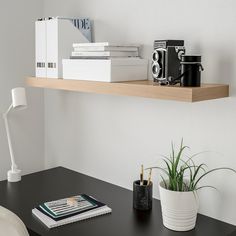 a desk with a book, camera and other items on the shelf next to it