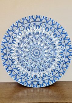 a blue and white plate sitting on top of a wooden table next to a wall