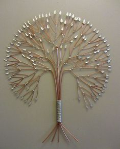 a metal tree with white leaves on it's branches is mounted to the wall