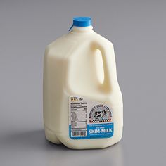 a gallon of milk sitting on top of a gray table next to a bottle of milk