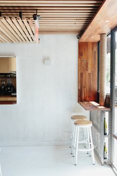 an empty room with two stools in front of a window and a bar area