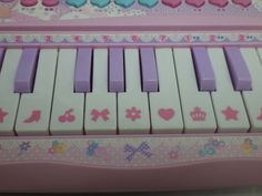 a pink toy piano with hearts and flowers on it