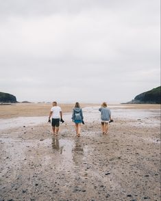 three people are walking on the beach together