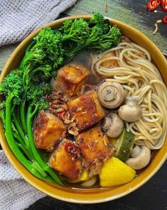 a bowl filled with noodles, broccoli and mushrooms