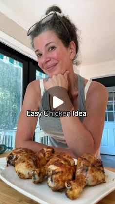 a woman sitting at a table in front of some chicken wings on a white plate