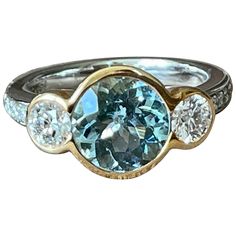 A timeless 18 K white Gold and rose Gold three Stone Ring featuring a bezel set Aquamarine wewighing approximately 2.50 ct. The centre stone is flanked by 2 bezel set brilliant cut Diamonds weighing 0.84 ct, G color, vs clarity. The ring size is currently a swiss 53/13 American Ring size 6 1/2, but can easily be resized. The ring is stamped with makers mark and 750. Masterfully handcrafted piece! Authenticity and money back is guaranteed. For any enquires, please contact the seller through the m Luxury Three Stone Sapphire Ring, Luxury Round Cut Gemstones With Center Stone, Luxury Round Cut Center Stone Gemstones, Luxury Three Stone Round Cut Sapphire Ring, Luxury Three Stone Gemstones For Anniversary, Three Stone Diamond Gemstones For Anniversary, Bezel Set Diamond Gemstones, Round Diamond Gemstones With Bezel Setting, Timeless Multi-stone Sapphire Ring