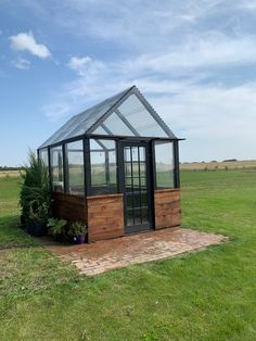 a small wooden and glass house in the middle of a field