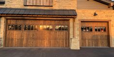 two garage doors are open in front of a house with stone and wood sidings