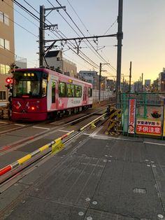 a red and white train traveling past tall buildings