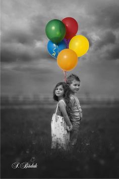 two young children are standing in the grass under a cloudy sky, one is holding an orange and white bag