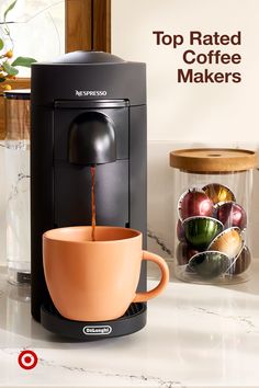 a coffee maker sitting on top of a counter next to a cup filled with liquid